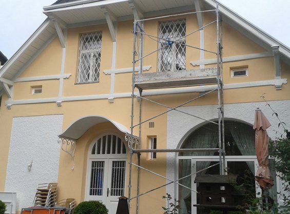 Frisch gestrichene Villenfassade in Ockergelb mit weißen Zierelementen