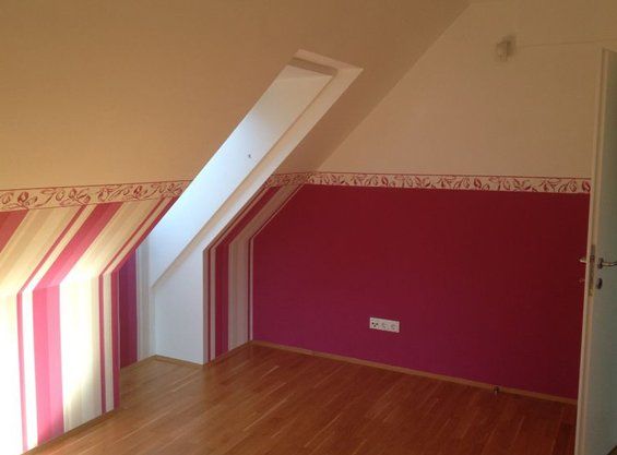 Dekorative Streifenwand in Korallrot und Magenta in einem Dachzimmer